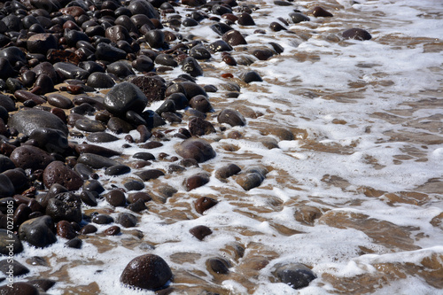 Olas rompiendo en las piedras de la orilla del mar photo