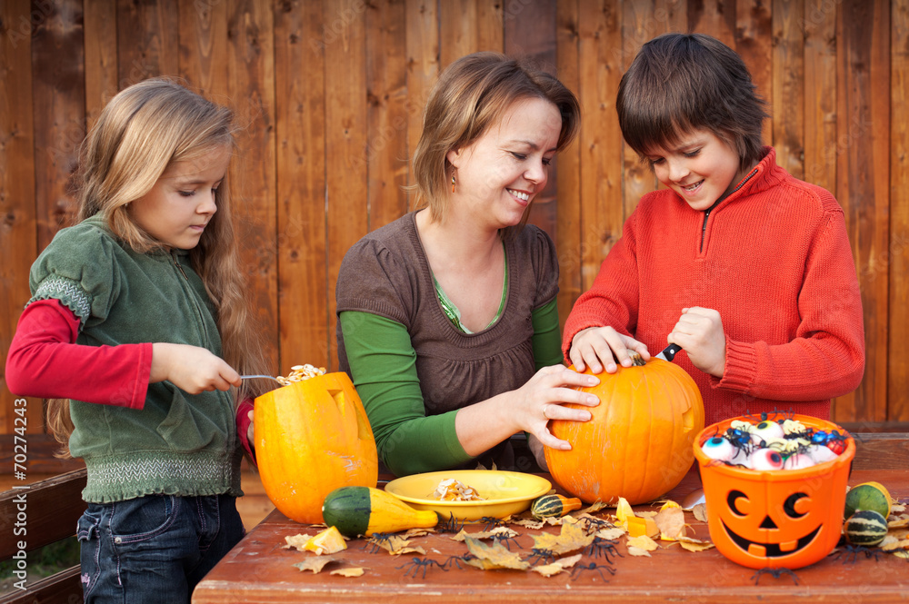 Fototapeta premium Woman helping kids to carve their Halloween jack-o-lantern