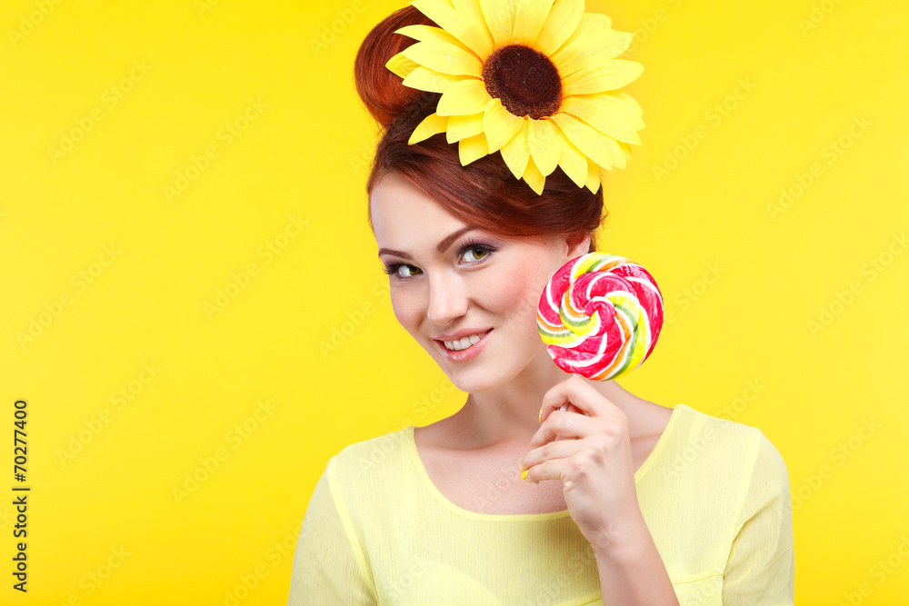 Beautiful girl with a large candy on a yellow 