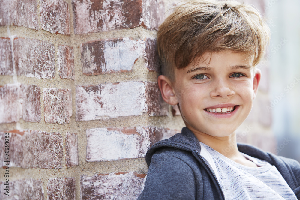 Portrait of young boy leaning against wall. Portrait of young boy leaning against wall.