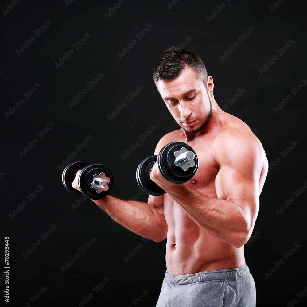 Portrait of a sportsman lifting dumbbells over black background