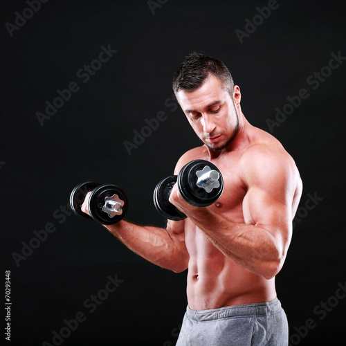 Portrait of a sportsman lifting dumbbells over black background