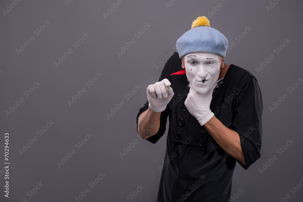 Portrait of young male mime with white face, grey hat showing em Portrait of young male mime with white face, grey hat showing em