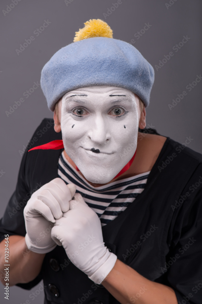 Portrait of young male mime with white face, grey hat showing em Portrait of young male mime with white face, grey hat showing em