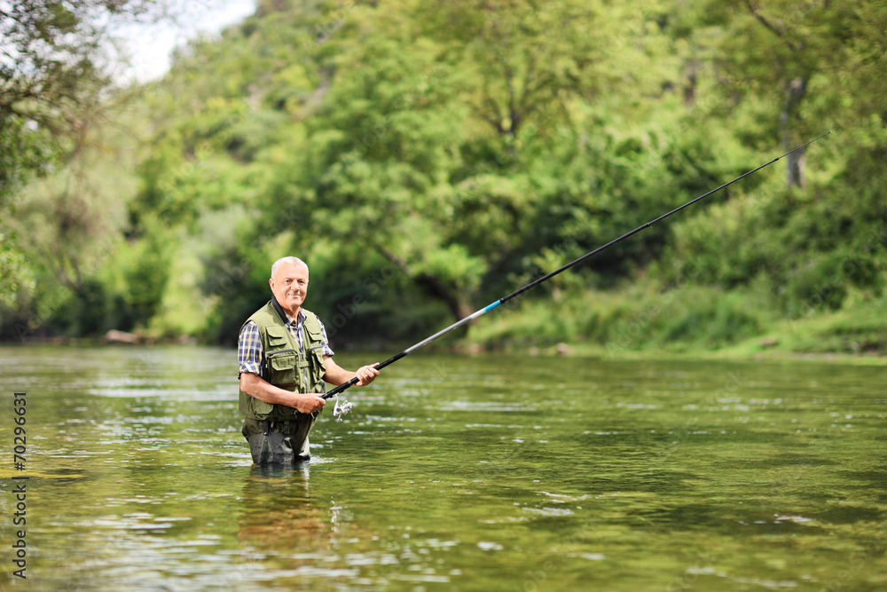 Senior man fishing in a river on a sunny day Senior man fishing in a river on a sunny day