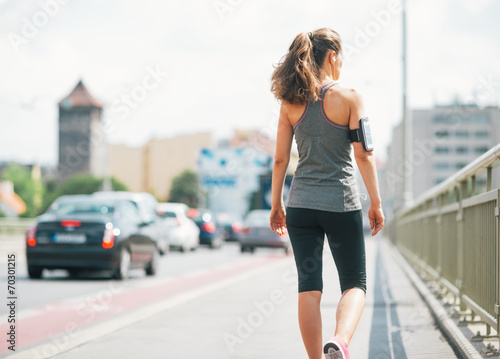 Fitness young woman walking in the city. rear view