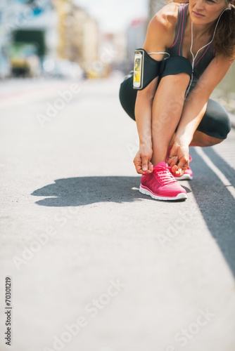 Closeup on fitness young woman tying shoelaces outdoors