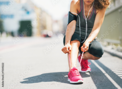 Closeup on fitness young woman tying shoelaces in the city