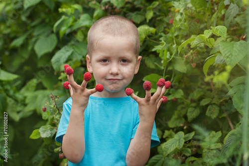 Portrait happy little child with raspberry outdoors