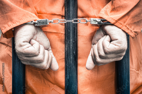 Foto Mit Handschellen gefesselte Hände eines Gefangenen hinter den Gitterstäben eines