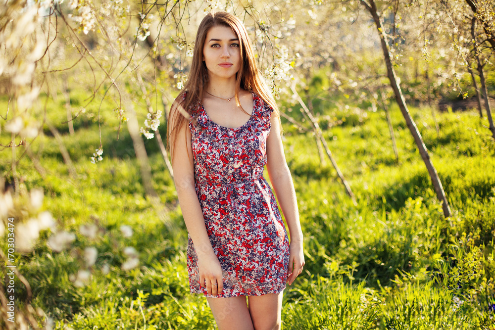 Beautiful young woman standing near blossom cherry trees