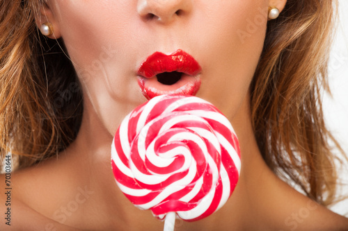 Surprised brunette with a red lollypop photo
