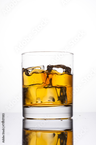 Whisky splashing in glass on a white background