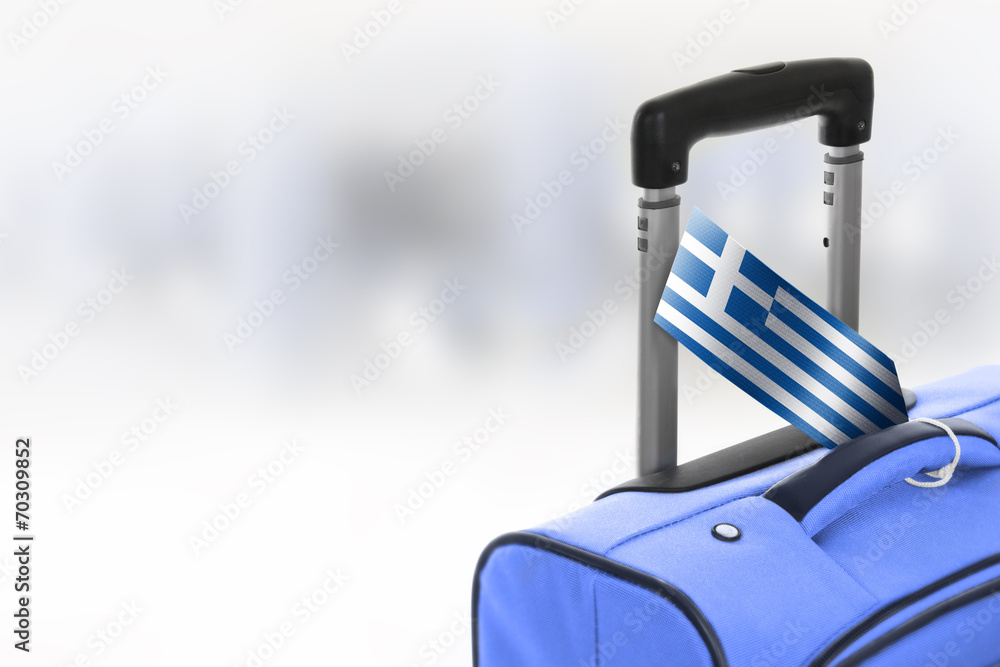 Obraz premium Destination Greece. Blue suitcase with flag.