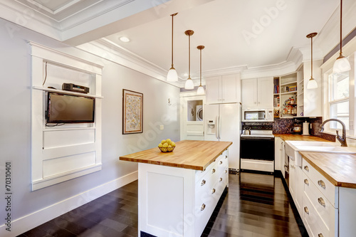 White kitchen with wooden counter top island and TV