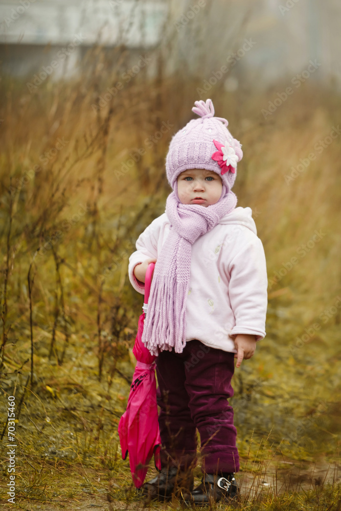 little girl  with pink umbrella in autumn park