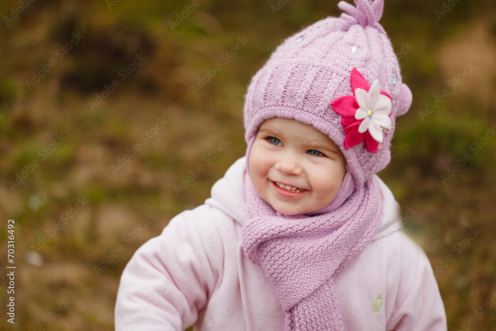 Happy baby girl in a pink hat and scarf laughs in autumn Happy baby girl in a pink hat and scarf laughs in autumn