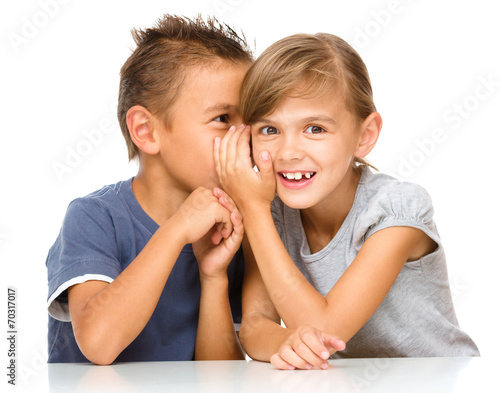 Little girl and boy are whispering in ear