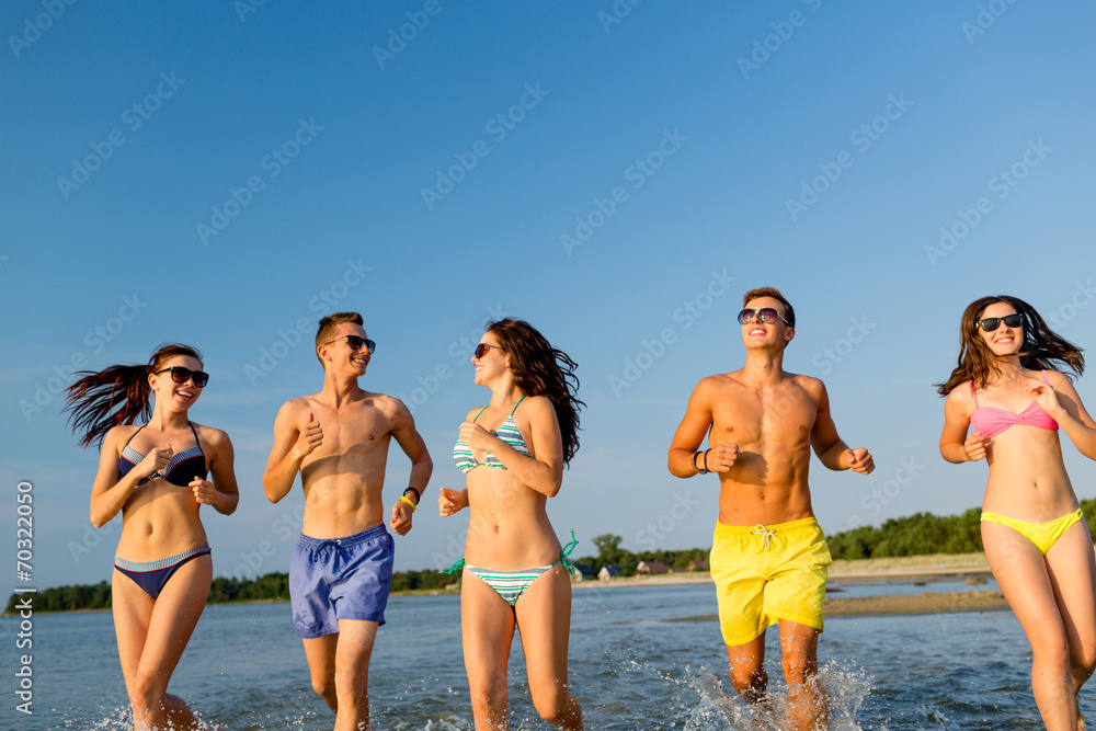 smiling friends in sunglasses running on beach smiling friends in sunglasses running on beach