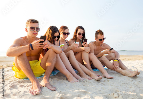 group of friends with smartphones on beach © Syda Productions