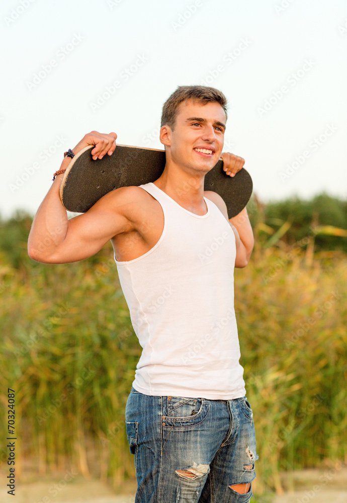 Fototapeta premium smiling teenage boy with skateboard outdoors