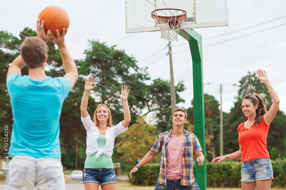 group of smiling teenagers playing basketball