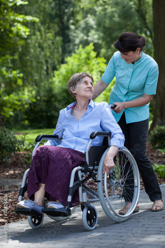 Disabled senior woman and nurse in park