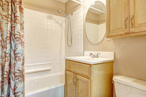 Light beige bathroom with wooden cabinets and floral curtain