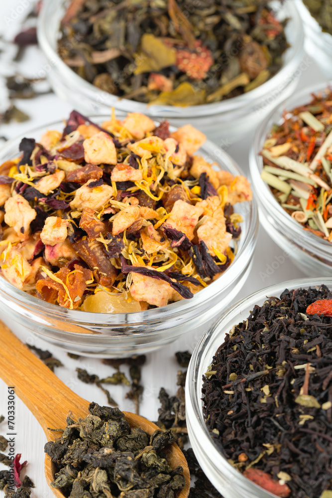 assortment of dry tea in glass bowls on wooden surface assortment of dry tea in glass bowls on wooden surface