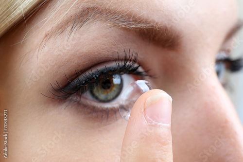 Medicine and vision concept - young woman with contact lens,