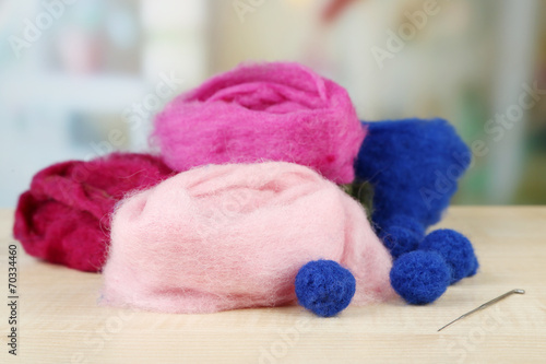 Wool for felting with needle on table on bright background © Africa Studio