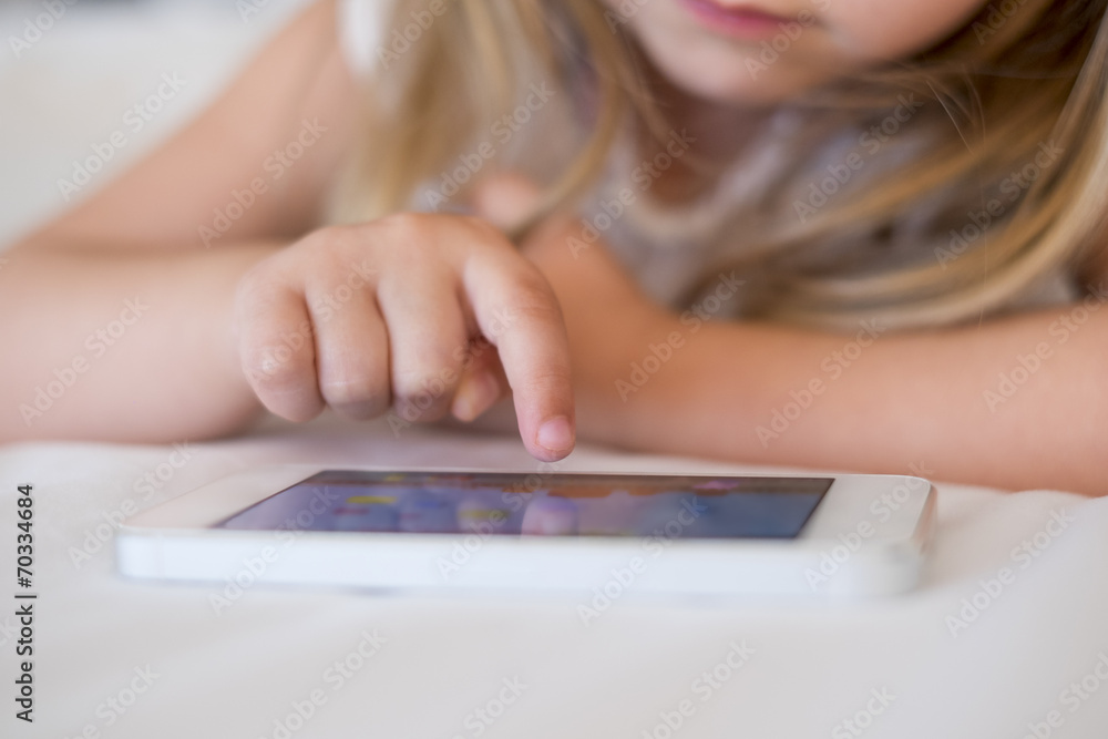 Fototapeta premium Cute Little girl using mobile phone at home