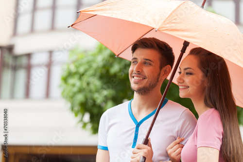 Portrait of woman and man standing under umbrella.