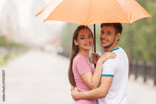 couple under umbrella standing turned around.