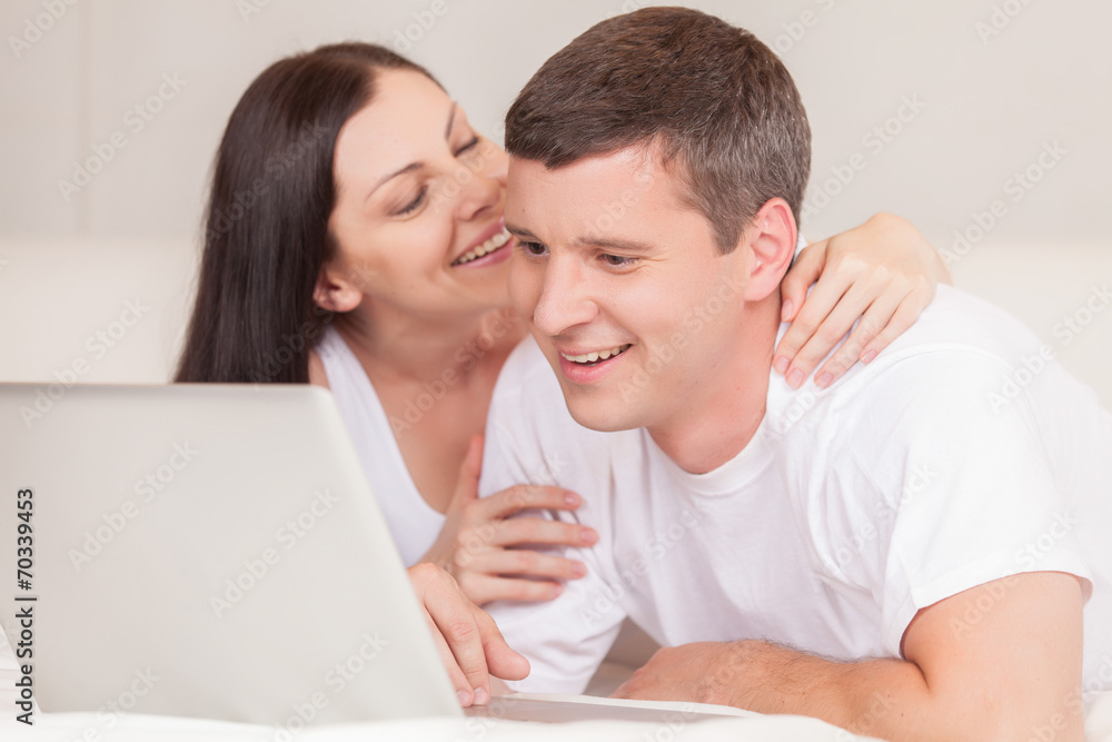 happy couple with laptop in bed smiling. happy couple with laptop in bed smiling.
