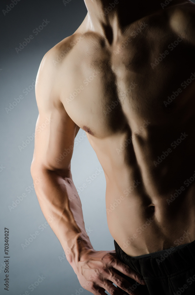 Muscular man posing in dark studio Muscular man posing in dark studio