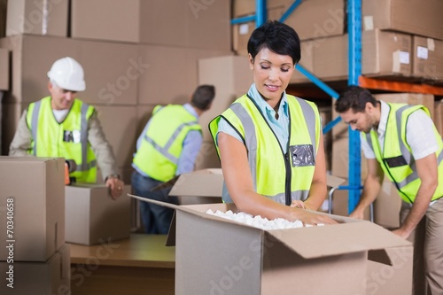 Warehouse workers in yellow vests preparing a shipment
