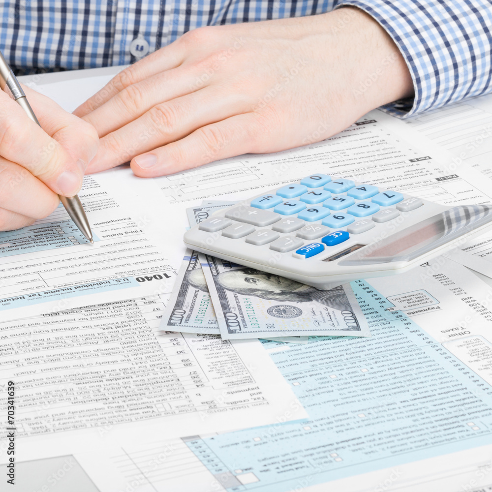 Obraz premium Male filling out 1040 USA Tax Form - studio shot - 1 to 1 ratio