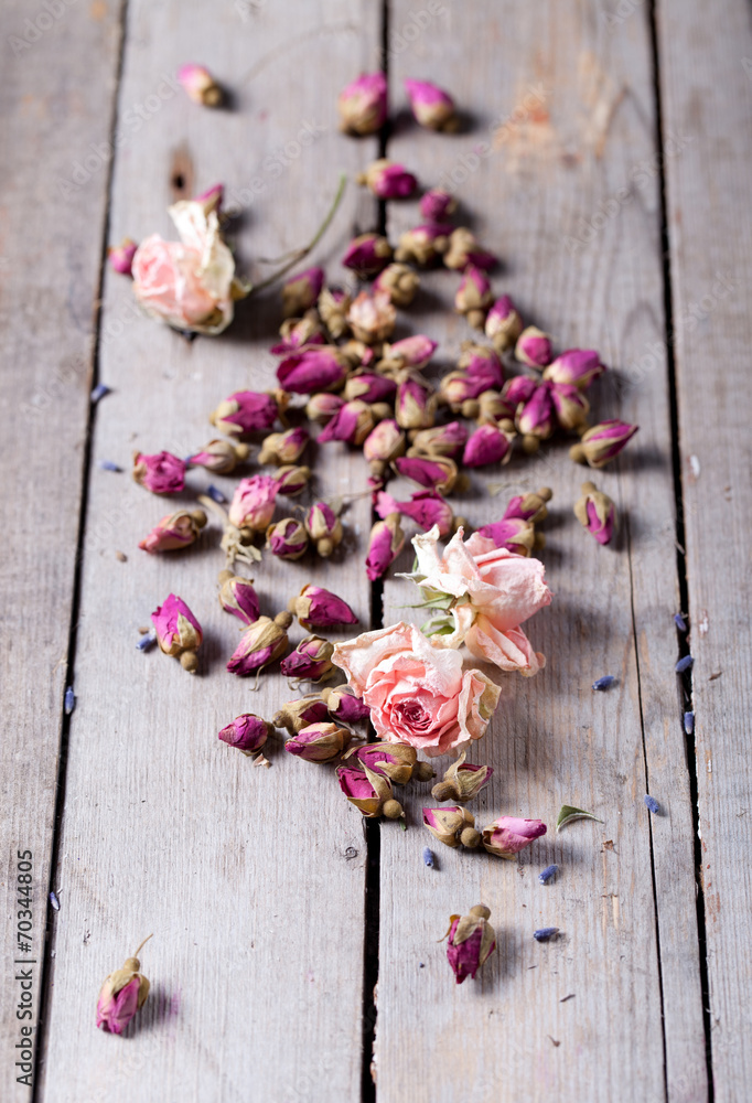 Dried rose buds scattered on a wooden table Dried rose buds scattered on a wooden table