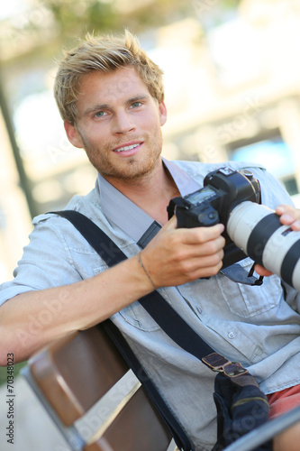 Young photographer with camera sitting on a bench