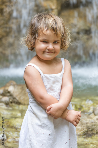cute smiling toddler child girl on waterfall background