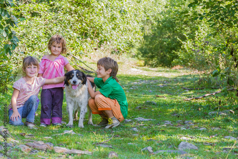 Obraz premium three kids - boy and girl - with dog outdoors