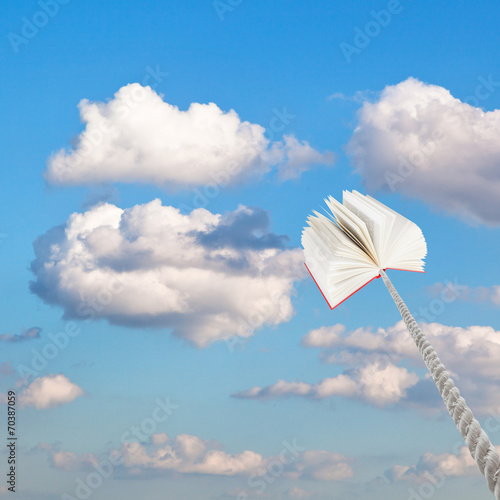 book tied on rope soars into little white clouds