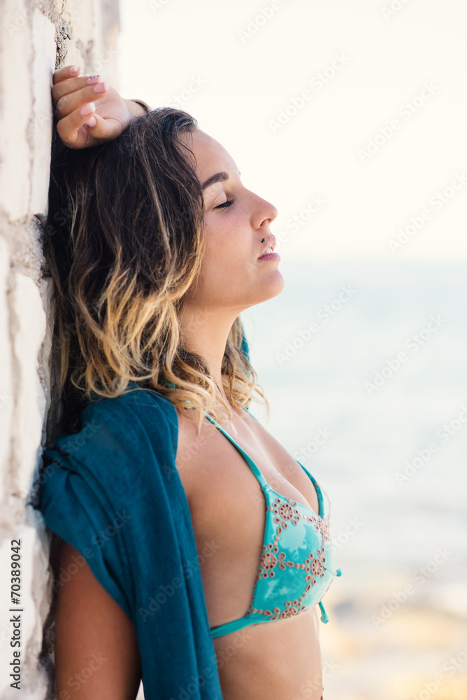 Sensual young woman wearing turquoise bikini posing at the sea.