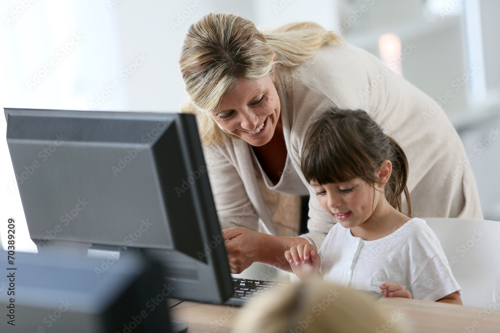 Teacher with little girl in class using computer and tablet Teacher with little girl in class using computer and tablet