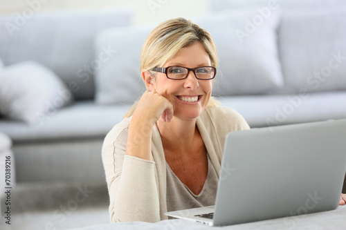 Mature woman with eyeglasses websurfing on laptop