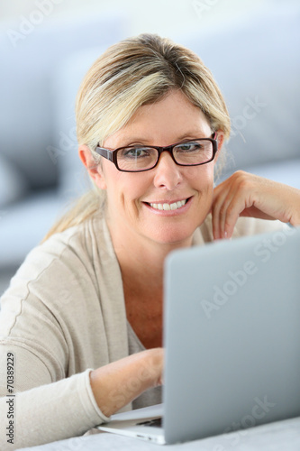 Mature woman with eyeglasses websurfing on laptop
