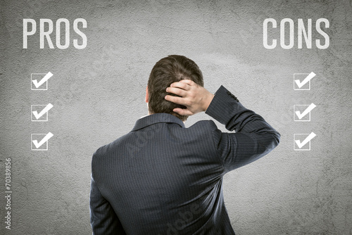 Businessman select all pros and cons in front of grey wall photo