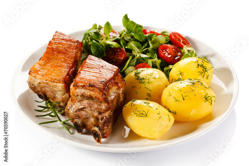 Tasty grilled ribs with vegetables on white background