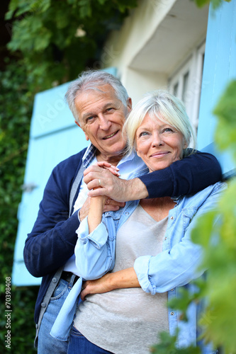 Senior man embracing his wife at house front door